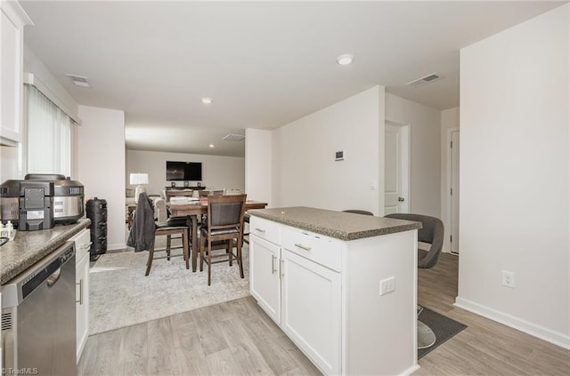 kitchen featuring light wood-type flooring, stainless steel dishwasher, and white cabinets