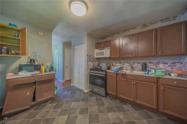 157 Blaze St, Winston-Salem, NC 27105 - kitchen with stainless steel range with gas cooktop, white microwave, a textured ceiling, backsplash, and light countertops