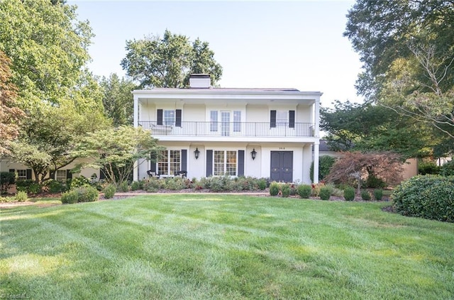 view of front of home with a balcony and a front yard