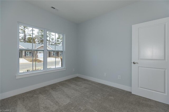 empty room with carpet flooring, baseboards, and visible vents