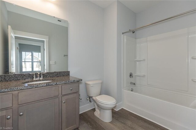 bathroom featuring tub / shower combination, baseboards, toilet, wood finished floors, and vanity