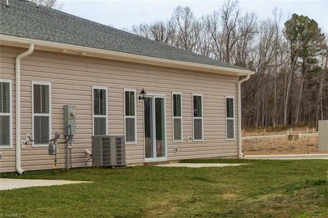 exterior space featuring a yard, central AC, and roof with shingles