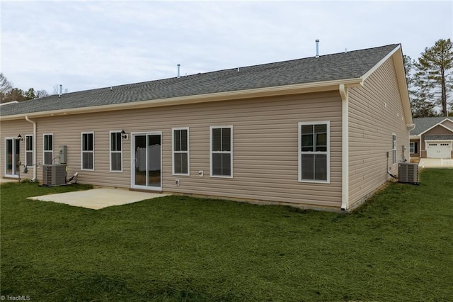 rear view of property with central AC unit, a patio, a yard, and roof with shingles