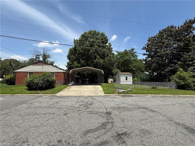 1611 Willow Rd, Greensboro, NC 27401 - view of front of house with a detached carport, asphalt driveway, a storage unit, and brick siding