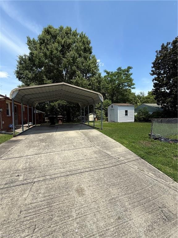 1611 Willow Rd, Greensboro, NC 27401 - view of parking featuring concrete driveway, a carport, and a storage unit