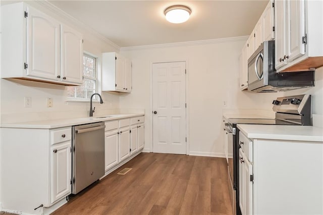 kitchen featuring white cabinetry, sink, stainless steel appliances, crown molding, and hardwood / wood-style flooring