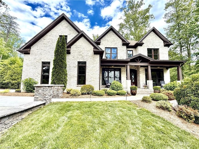view of front of property with covered porch, a front yard, and brick siding