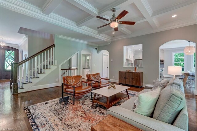 living room featuring arched walkways, a ceiling fan, wood finished floors, ornamental molding, and baseboards