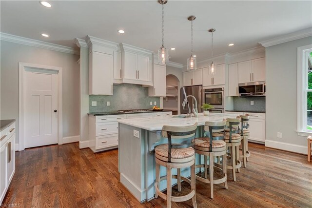 kitchen with stainless steel appliances, a sink, decorative backsplash, ornamental molding, and white cabinets