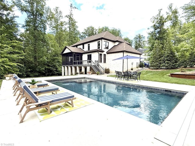 swimming pool featuring a sunroom, stairs, a patio, and a lawn