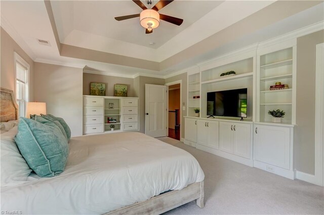 bedroom featuring a raised ceiling, light carpet, and a ceiling fan