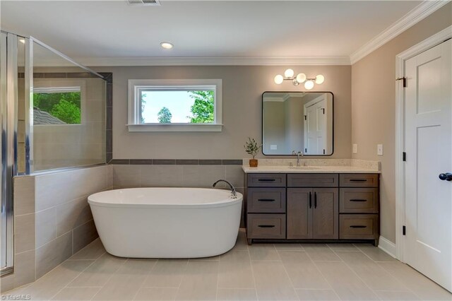 bathroom featuring a freestanding bath, vanity, crown molding, tile patterned flooring, and tile walls