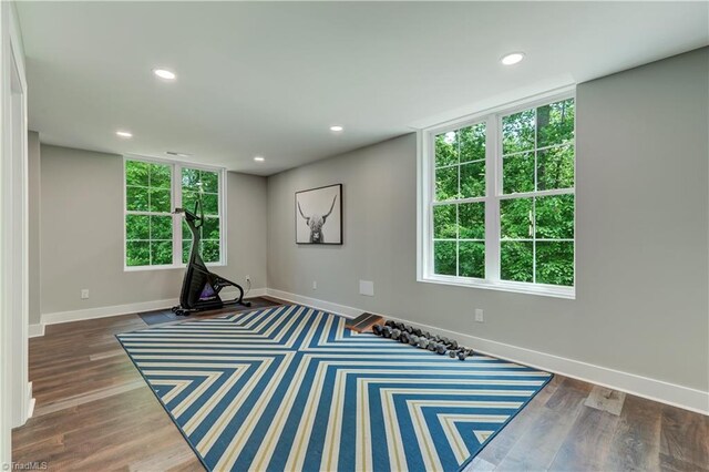 exercise room featuring baseboards, wood finished floors, and recessed lighting