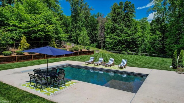view of pool with a patio and a wooded view