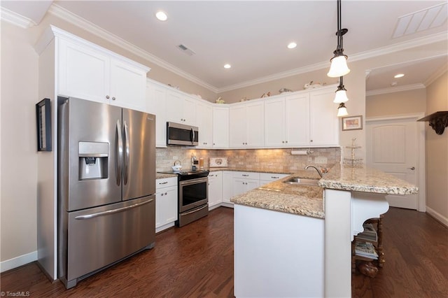 kitchen featuring kitchen peninsula, appliances with stainless steel finishes, dark hardwood / wood-style floors, decorative light fixtures, and crown molding