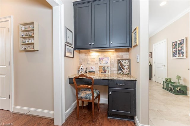 bar with built in desk, ornamental molding, wood-type flooring, blue cabinets, and decorative backsplash