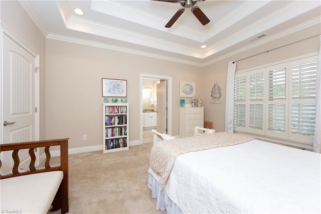 bedroom with ornamental molding, ensuite bath, light carpet, a tray ceiling, and ceiling fan