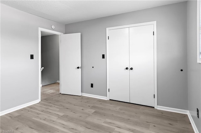 unfurnished bedroom featuring baseboards, a closet, and light wood-style flooring
