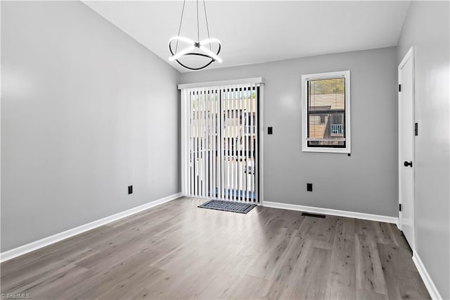interior space featuring baseboards, a chandelier, wood finished floors, and plenty of natural light