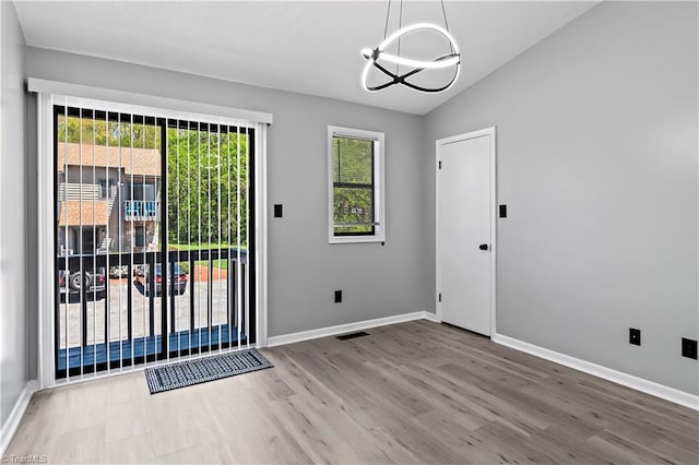 interior space with lofted ceiling, wood finished floors, visible vents, baseboards, and a chandelier