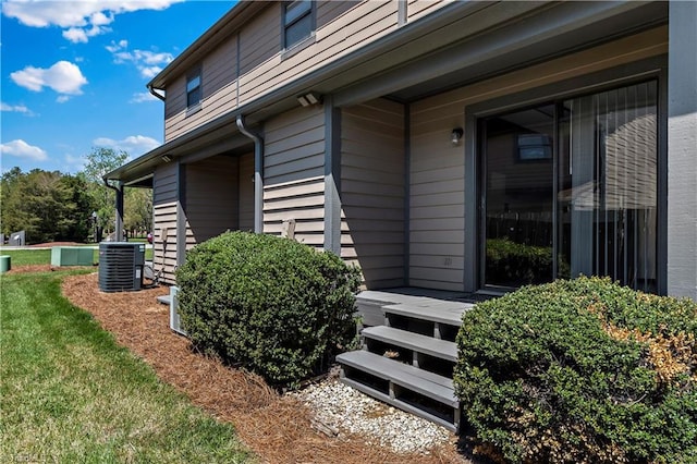 property entrance with central air condition unit and a yard
