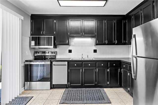 kitchen with dark cabinets, stainless steel appliances, a sink, and dark countertops
