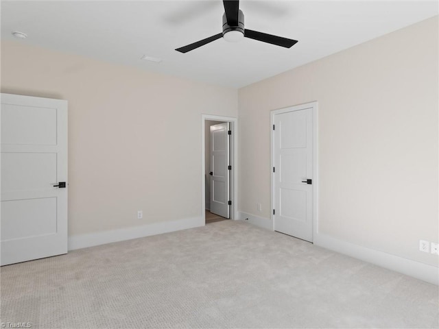 unfurnished bedroom with light carpet, a ceiling fan, and baseboards