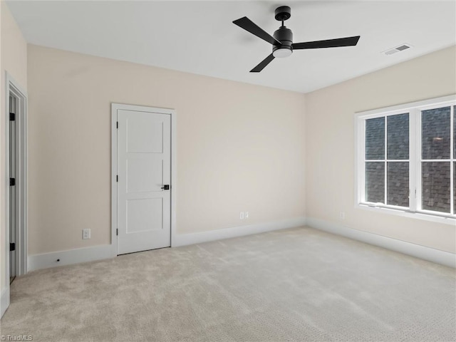 empty room featuring baseboards, ceiling fan, visible vents, and light colored carpet