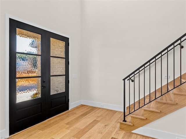 foyer with french doors, stairway, baseboards, and wood finished floors