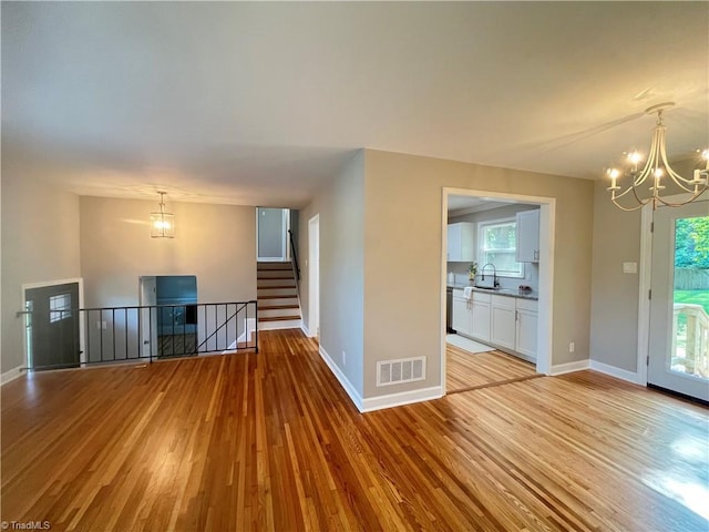 100 Petree Rd, Winston-Salem, NC 27106 - unfurnished living room with a chandelier, light wood-style floors, plenty of natural light, and stairway
