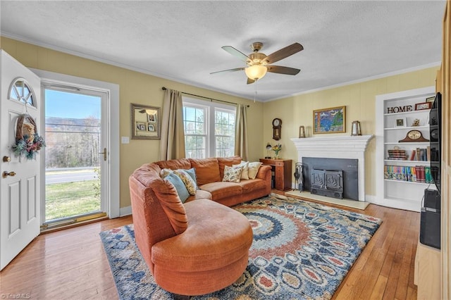 1109 Wildwood Rd NE, Lenoir, NC 28645 - living area with ornamental molding, a textured ceiling, hardwood / wood-style flooring, a fireplace with raised hearth, and ceiling fan