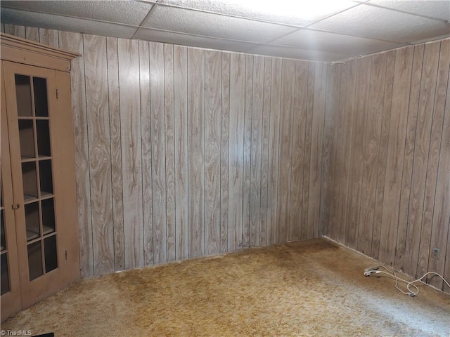 spare room featuring carpet floors, a paneled ceiling, and wood walls