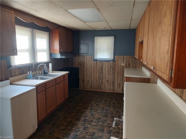 kitchen featuring a drop ceiling, sink, and wooden walls