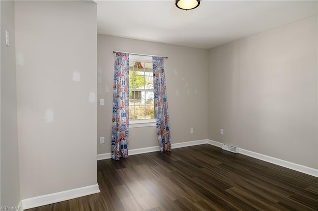 spare room featuring dark wood-style floors, visible vents, and baseboards