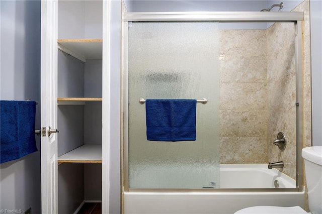 bathroom featuring enclosed tub / shower combo and toilet