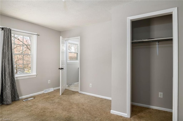 unfurnished bedroom featuring a textured ceiling, carpet flooring, visible vents, and baseboards