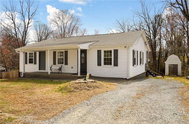 view of front facade featuring an outbuilding, a porch, fence, driveway, and a shed