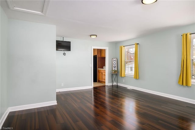 empty room with attic access, baseboards, and wood finished floors