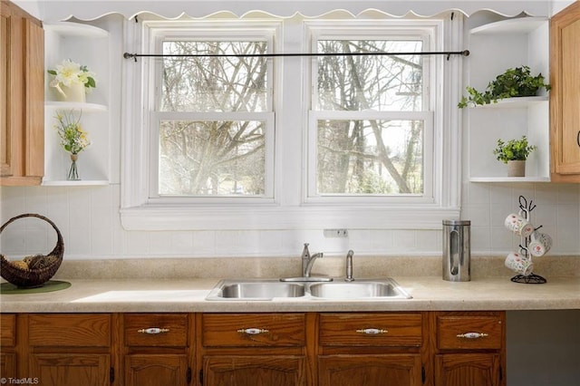 kitchen featuring a sink, light countertops, a wealth of natural light, open shelves, and tasteful backsplash