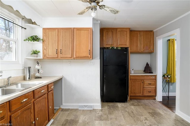 kitchen with open shelves, light countertops, a sink, and freestanding refrigerator