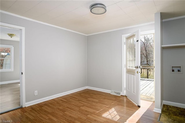 interior space with ornamental molding, visible vents, baseboards, and wood finished floors