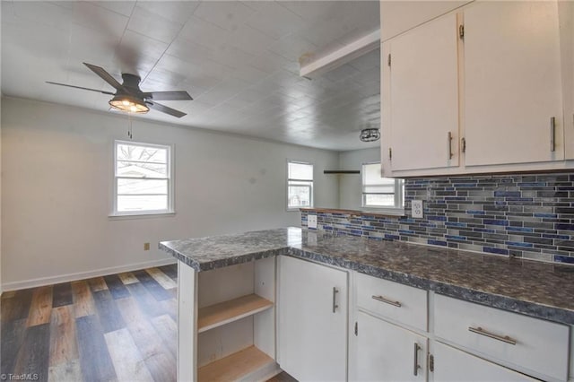 kitchen with dark stone countertops, white cabinets, dark hardwood / wood-style flooring, backsplash, and kitchen peninsula