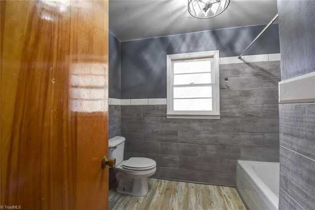 bathroom featuring hardwood / wood-style floors, a tub, tile walls, and toilet