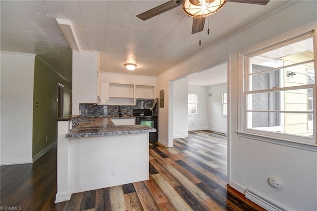 kitchen featuring white cabinets, backsplash, a baseboard heating unit, kitchen peninsula, and black electric range