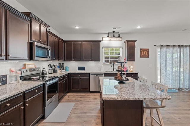 371 Royce Dr, Winston-Salem, NC 27107 - kitchen with a kitchen island, a kitchen bar, a sink, light wood finished floors, and appliances with stainless steel finishes