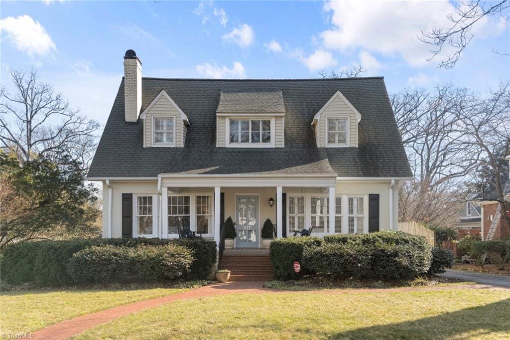 new england style home featuring a porch and a front yard