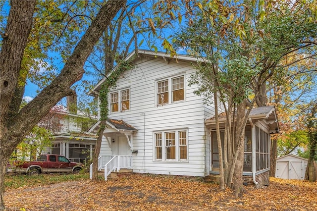 view of front of home with a sunroom and a storage shed