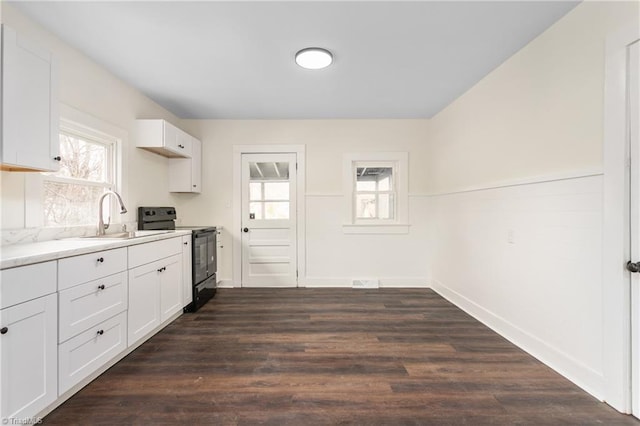 kitchen with dark wood-type flooring, light countertops, black electric range, white cabinetry, and a sink