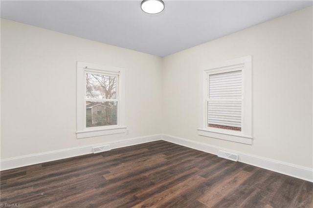 unfurnished room featuring visible vents, baseboards, and dark wood-style flooring