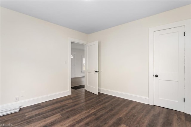 spare room featuring dark wood finished floors and baseboards